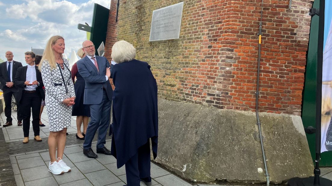 Beatrix kijkt naar de plaquette waarop staat dat Prins Claus in 1990 de molen opende na de restauratie