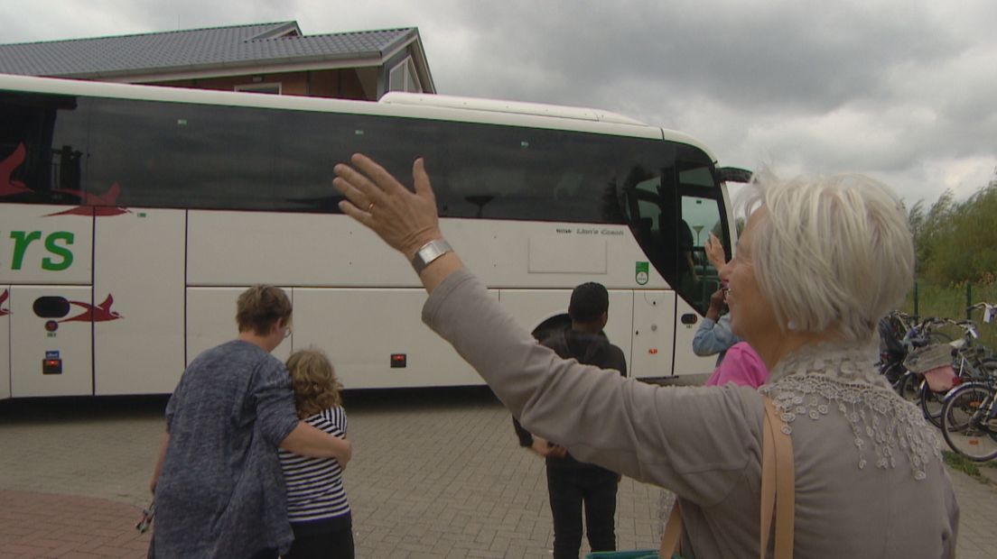Toos de Visser zwaait de bus met vluchtelingen uit