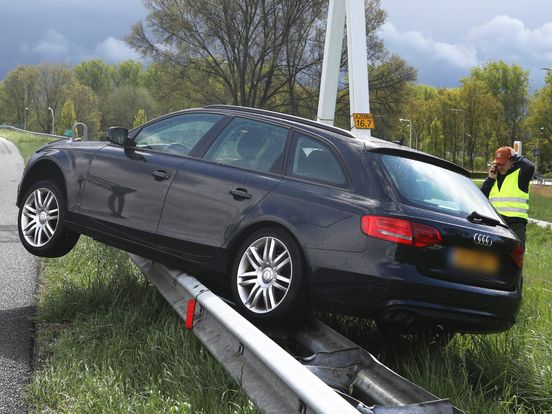 Auto eindigt bovenop vangrail langs snelweg