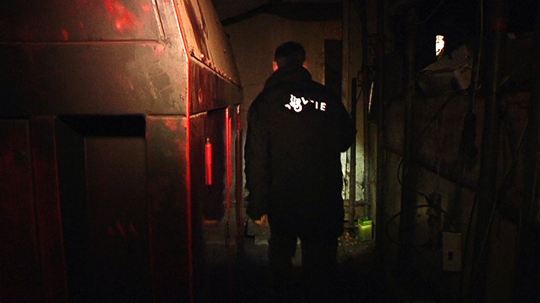 Rechercheur loopt langs een dieselagregaat in de ondergrondse kwekerij.