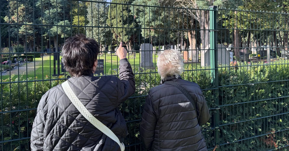 Begraafplaats dicht vanwege storm: bezoekers met bloemen staan voor een gesloten poort