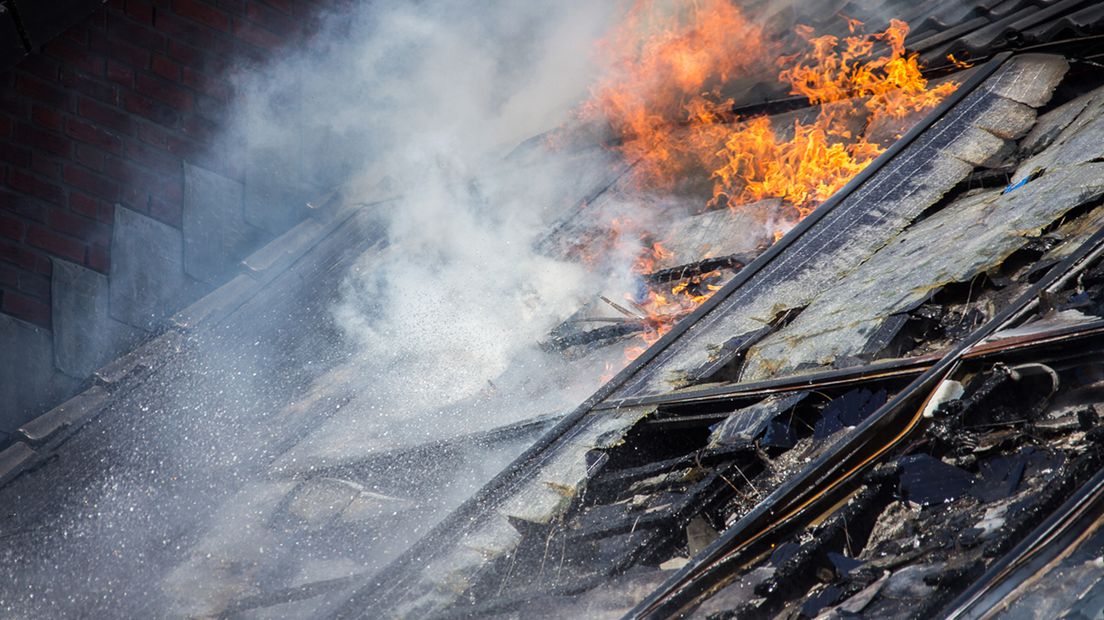 De daken van de woningen zijn flink beschadigd door de brand.