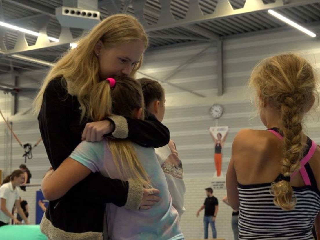 Jasmijn knuffelt één van haar pupillen bij turnvereniging Doto