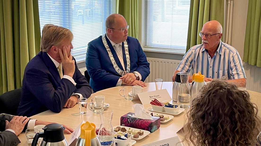 De koning en burgemeester Visser praten met een inwoner van Loppersum