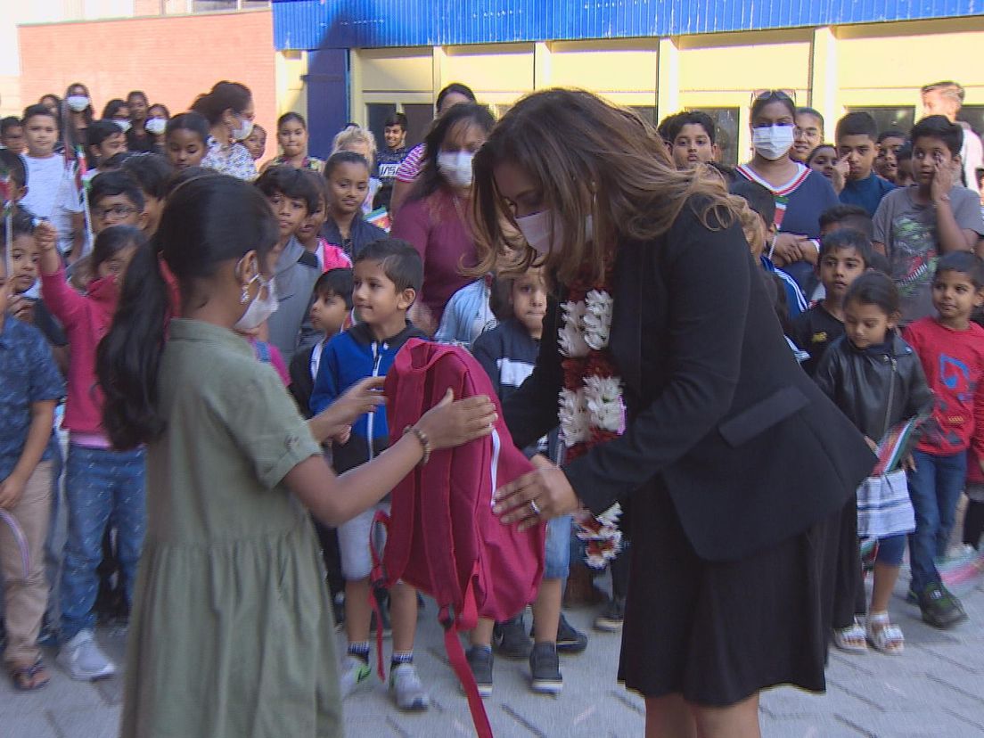 De Surinaamse 'first lady' krijgt een schooltas overhandigt.