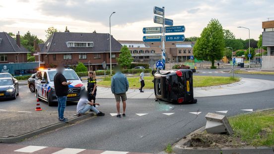 Auto raakt betonblok en belandt op z'n kant op rotonde
