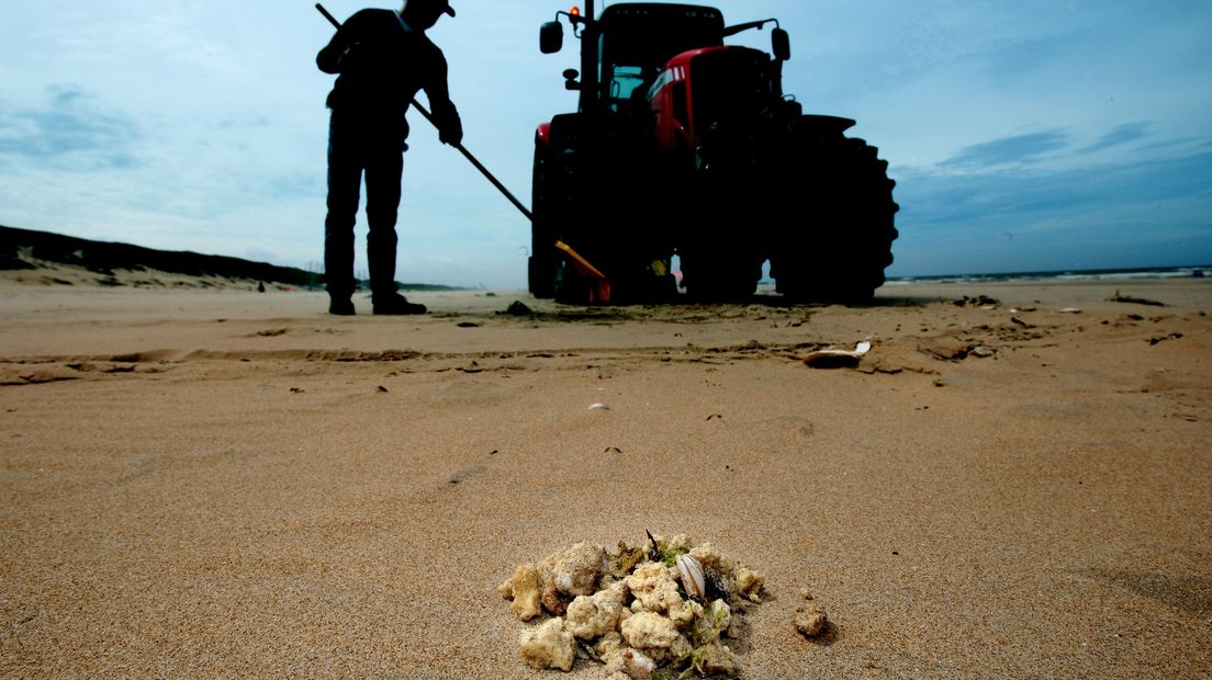 Op een strand wordt paraffine opgruimd