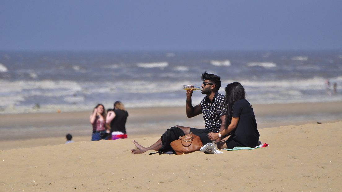 Badgasten genieten van de zomerse zon op het Scheveningse strand
