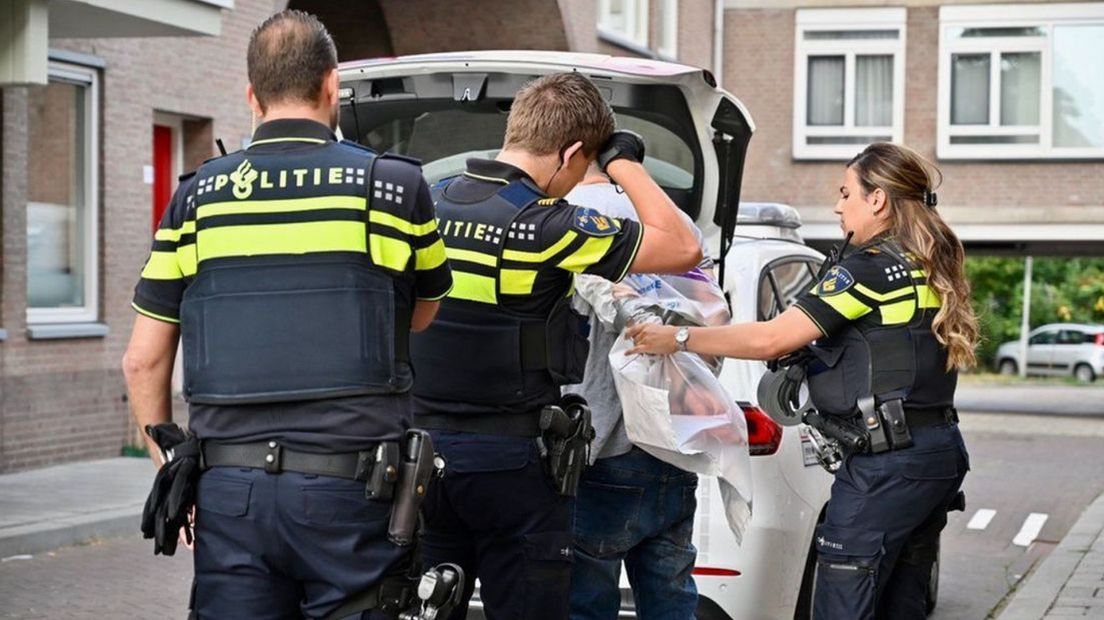 De politie houdt de man aan na zijn daad in de Tuinstraat in Arnhem.