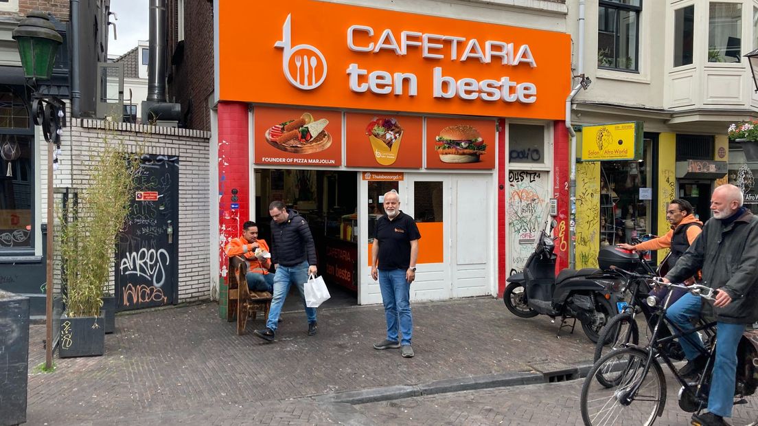 Arif Alkan voor zijn cafetaria, op de gevel: 'Founder of Pizza Marjolein'