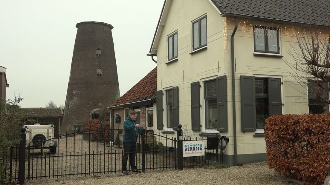 Wim Derksen bij zijn huis met de onttakelde molen op de achtergrond.