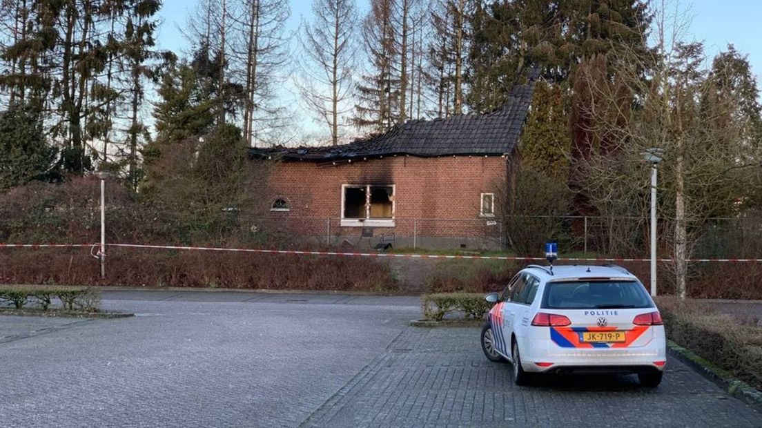 De politie bewaakt de afgebrande woning.