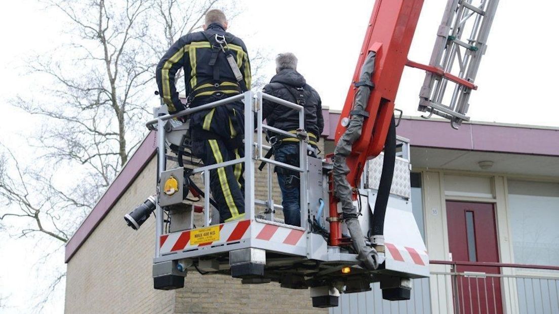 Met een hoogwerker wordt op het dak van de woning gezocht