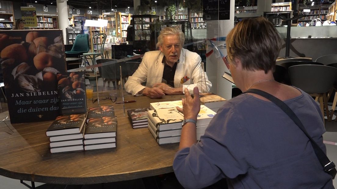 Auteur Jan Siebelink signeerde zaterdag met een plexiglazen wandje tussen hem en de bezoekers.