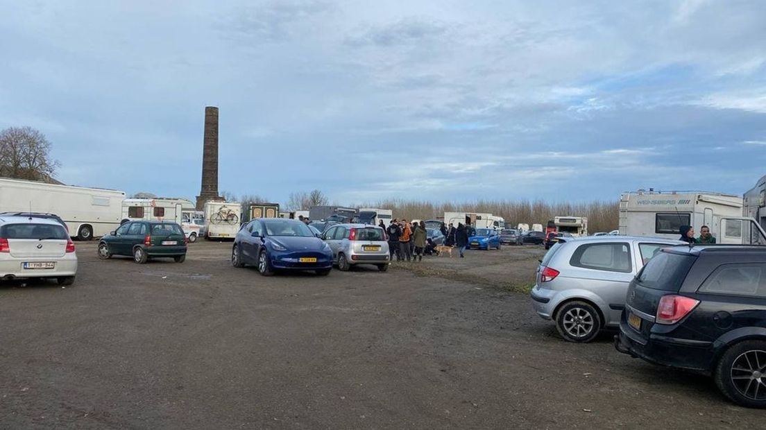 In de omgeving van de loods staan veel geparkeerde auto's en kampeerwagens.