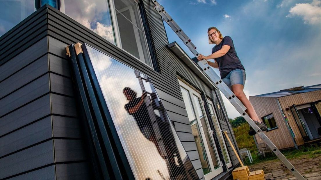 Demi Martens op de ladder bij haar tiny house in Harderwijk.