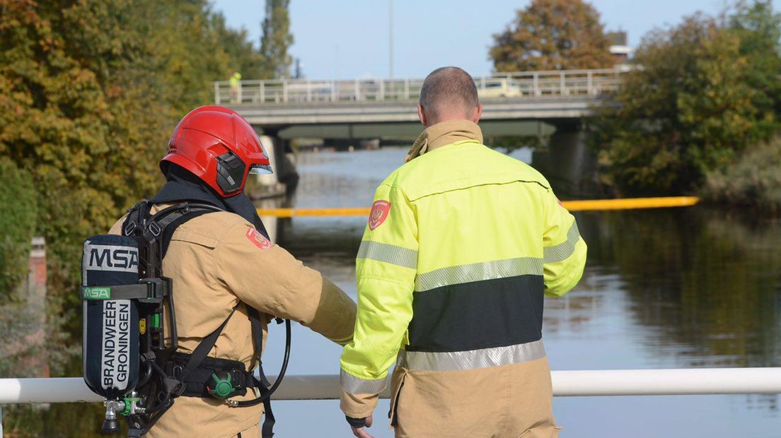 Brandweerlieden zetten het water aan de Koestraat in Farmsum af na het olielek.