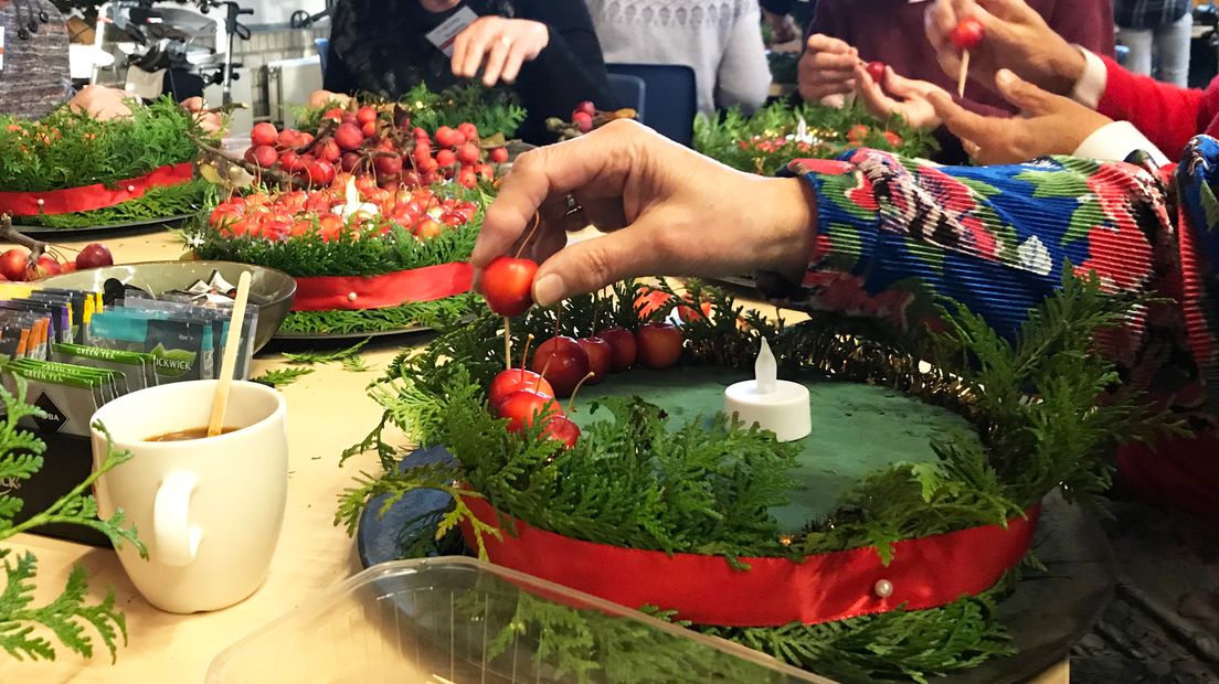 Het kerststuk wordt versierd met appeltjes.