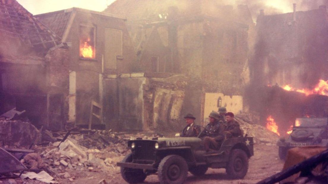 Acteur Laurence Olivier rijdt met zijn Jeep over de in brand staande Muggeplein in Deventer