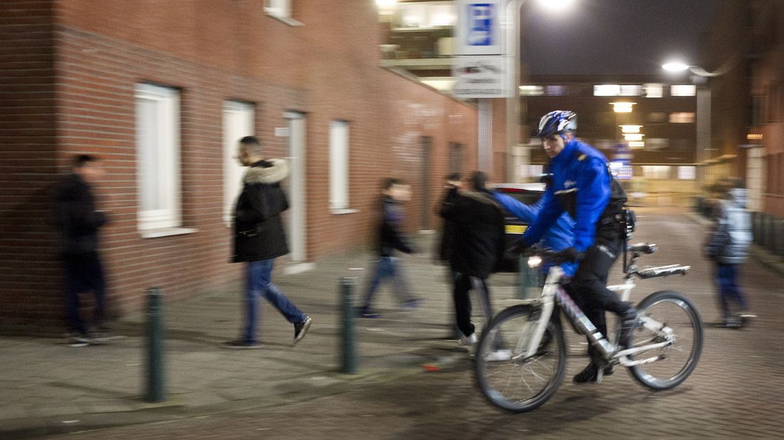 Een politieman fietst langs jongeren in de Haagse Schilderswijk