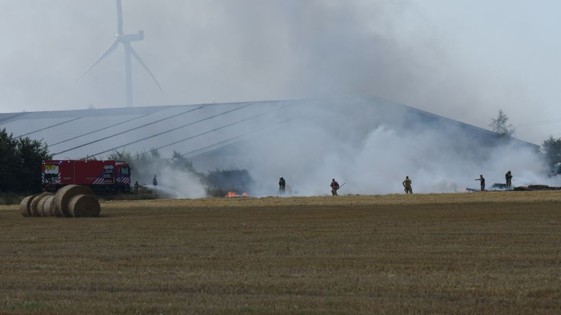 Brandweerlieden proberen de brand in het weiland te bedwingen