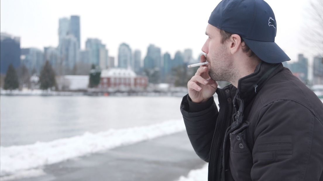 Jacob Lensky geniet van een sigaret met op de achtergrond de skyline van Vancouver