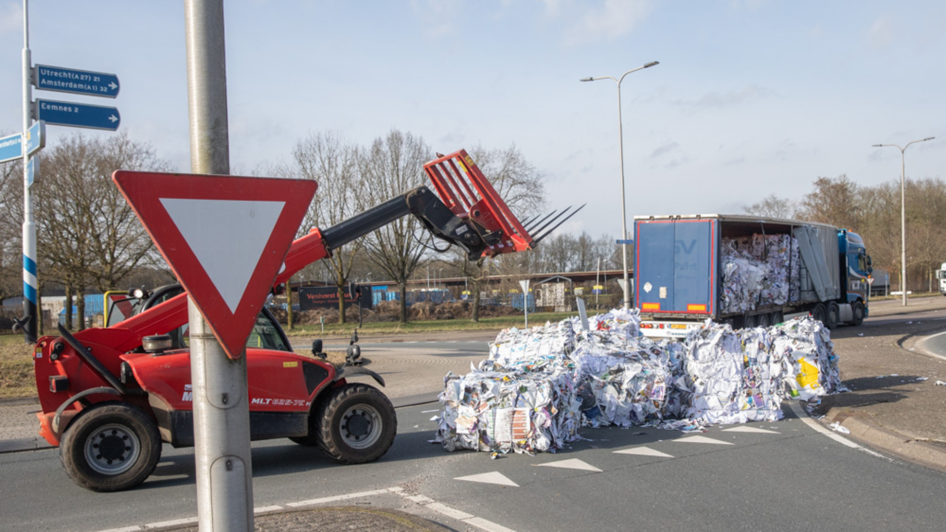 Vrachtwagen verliest balen papier op rotonde in Baarn