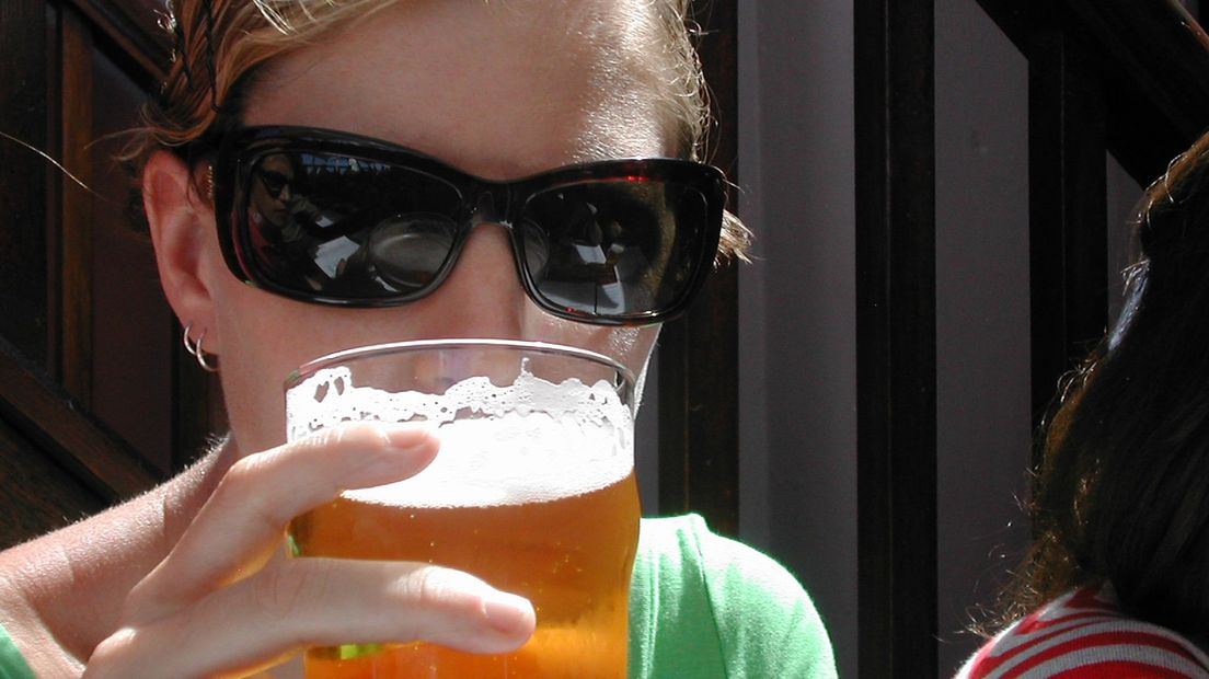 Een vrouw neemt een slok van haar bier.
