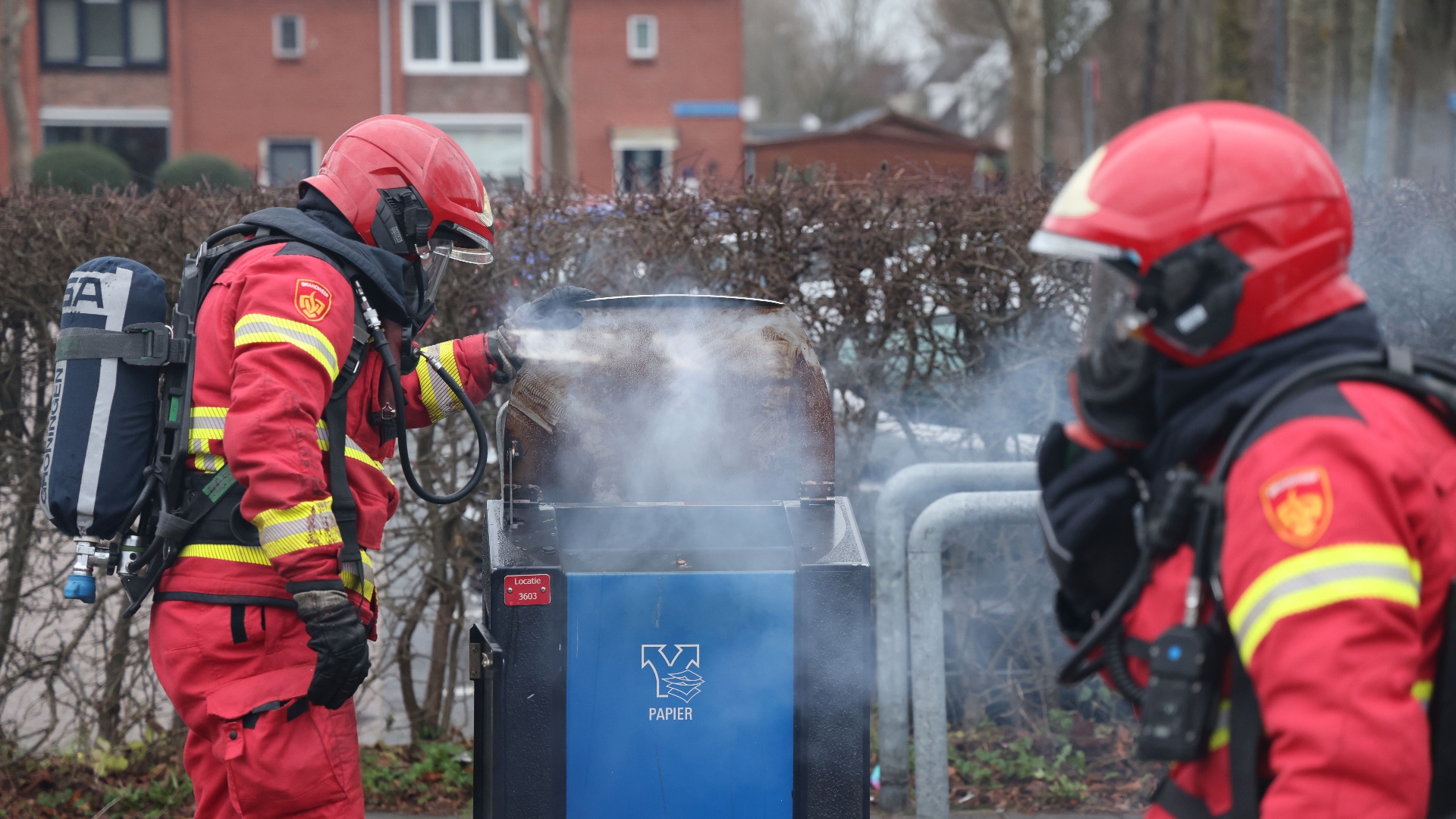 De brandweer blust de brand in een afvalcontainer in Stad