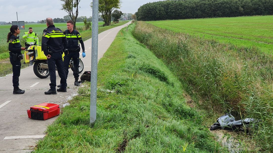 Agenten nemen poolshoogte bij de plek waar de bromfietser in de sloot belandde.