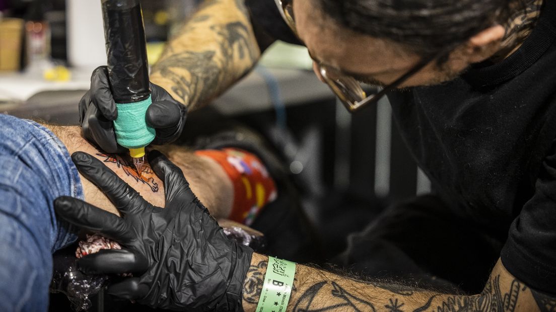 Een tatoeëerder zet een tattoo bij een klant