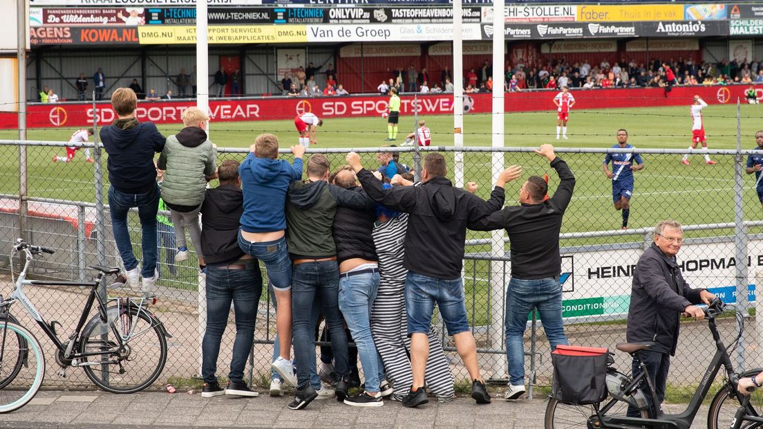 Voetbalsupporters bij de hekken van de Westmaat.