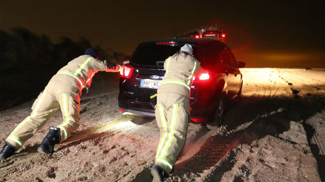 Brandweermannen helpen om de auto weer los trekken