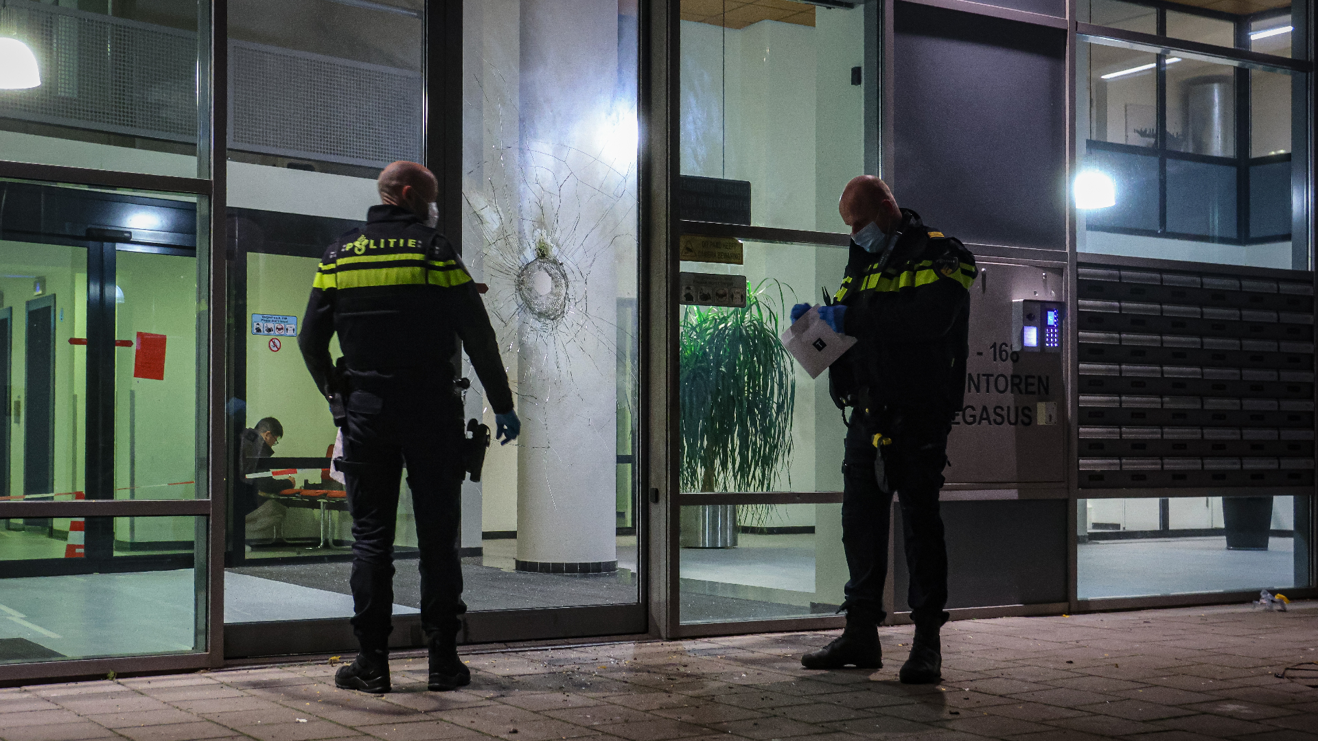 De portiekdeur raakte flink beschadigd door de explosie.