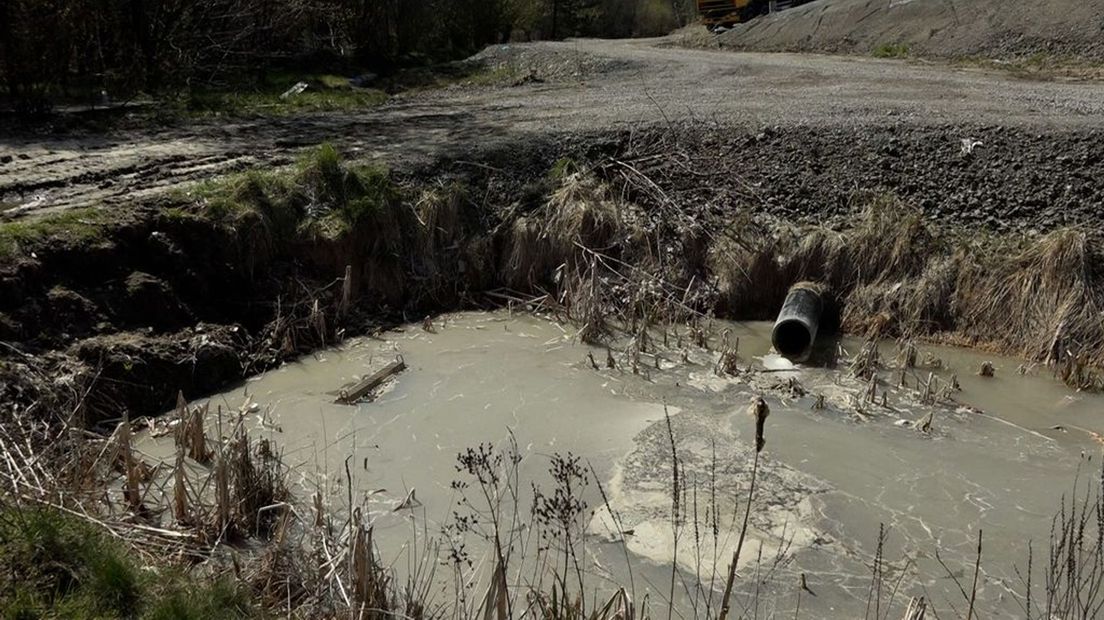 Sloot met vervuild water overstroomt, vervuild water loopt de natuur in.