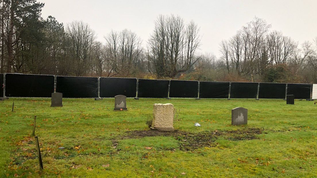Het grafveld dat wordt geruimd, is afgezet met schermen