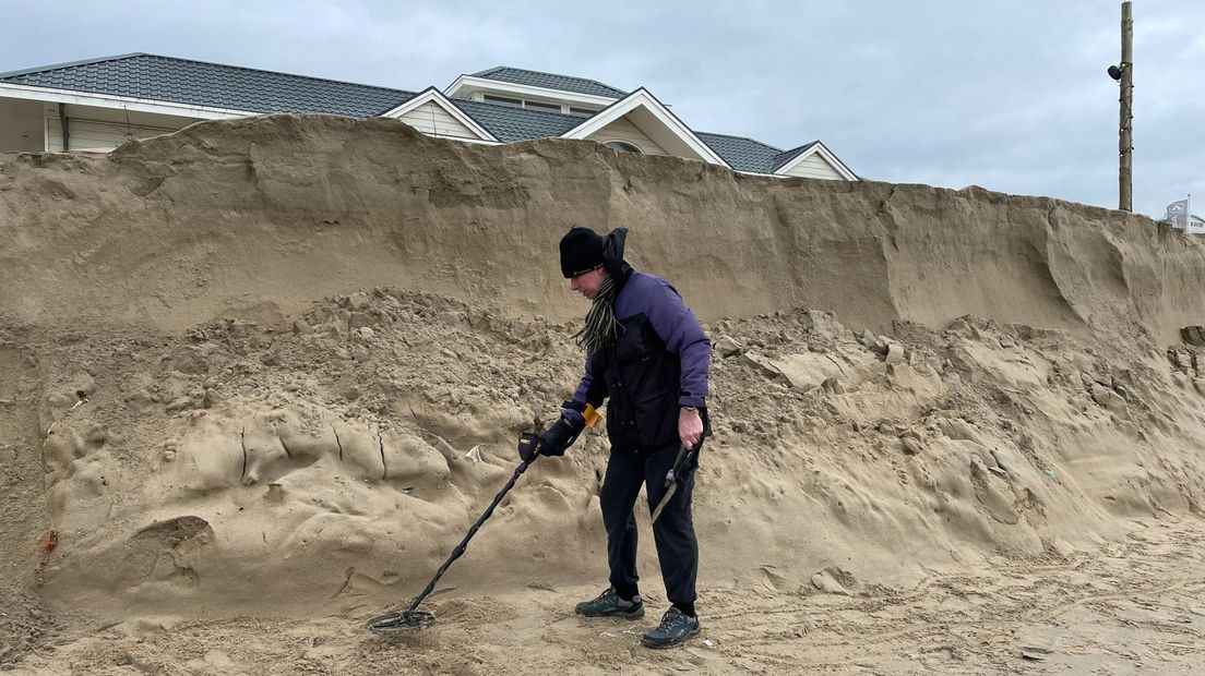 Een man met een metaaldetector op het strand van Noordwijk na storm Corrie.