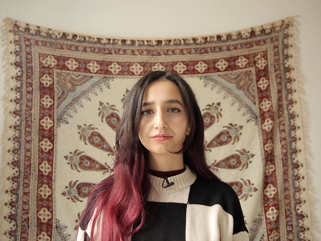 Mina Morkoç met op de achtergrondd een Iraans tapijt