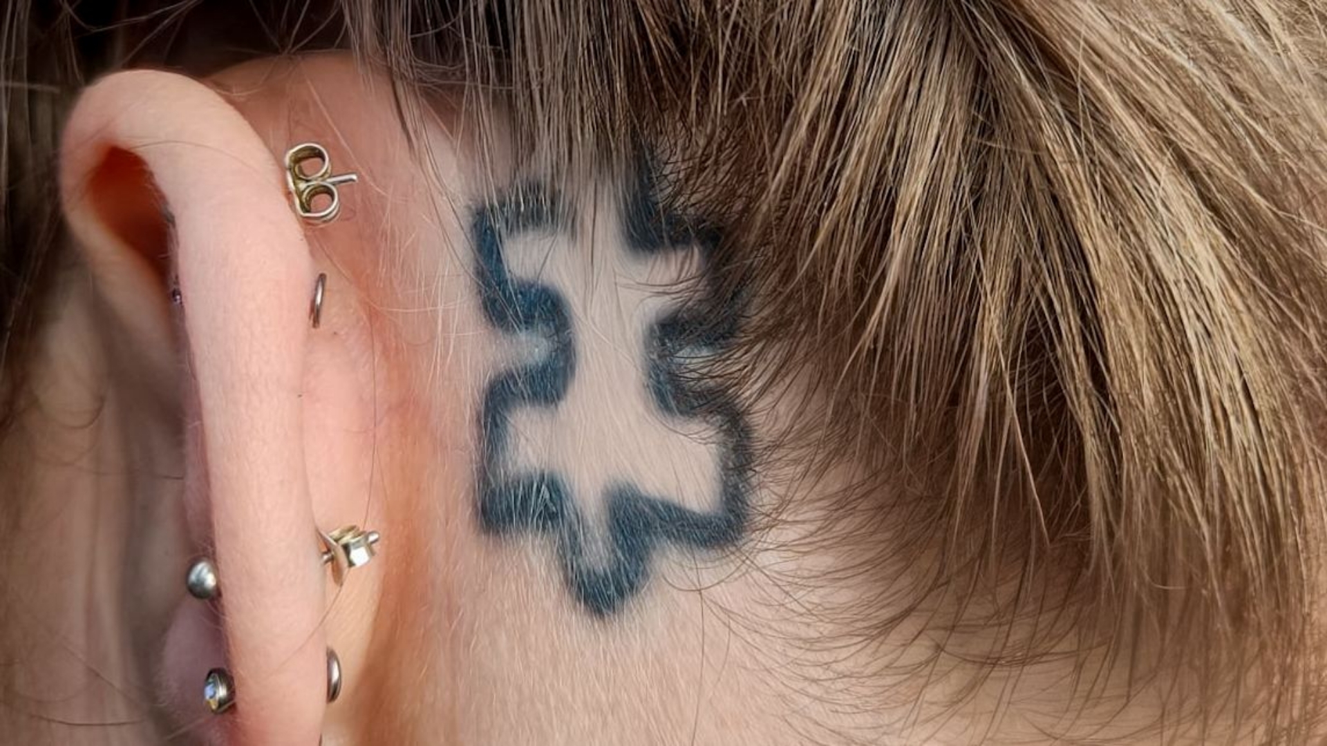 Een tatoeage van een puzzelstukje, het logo van de autismevereniging, op het hoofd van Inge