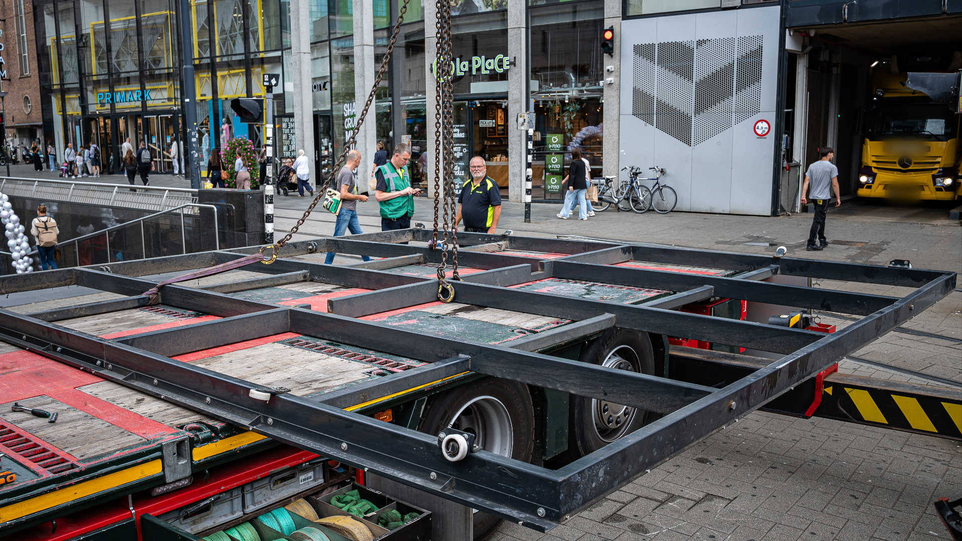 Een vrachtwagen met kraan heeft de garagedeur van straat gehaald. De panelen zijn los van de deur gehaald.