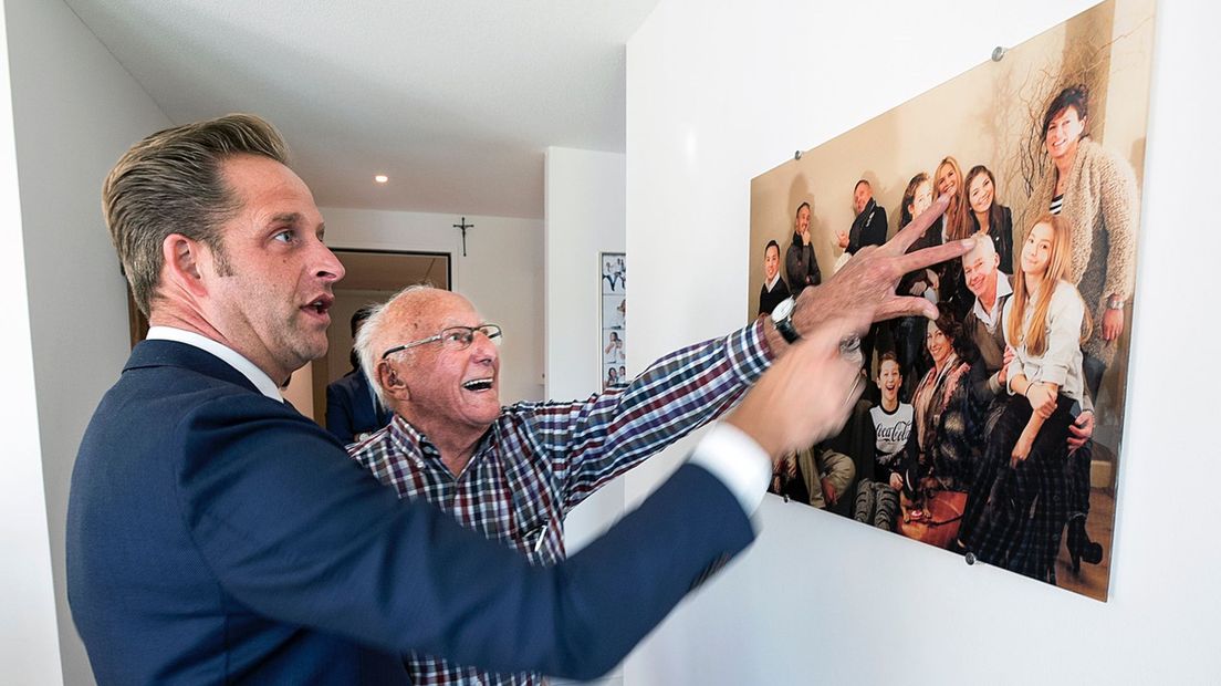 Theo van Vliet, bewoner van Gastenhuis Vleuten, geeft minister Hugo de Jonge een toelichting bij een foto van zijn familie.