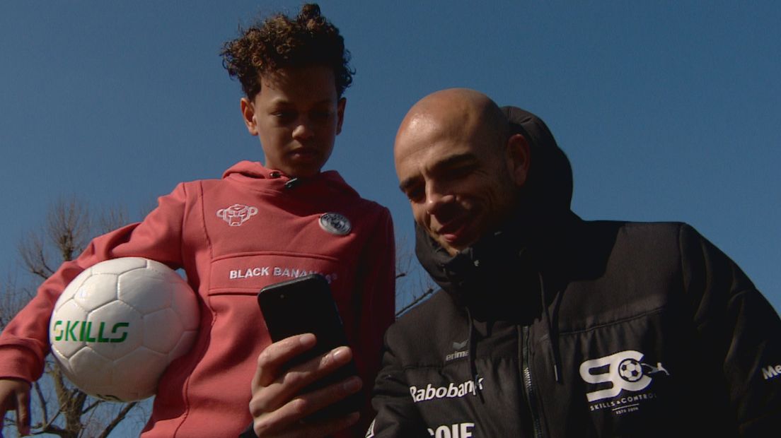 Reguillo Vandepitte laat app zien aan Ilaï Grootfaam, jeugdvoetballer van Ajax