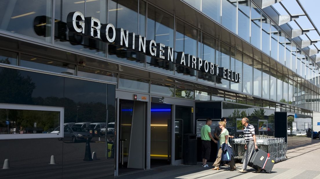 Twee bezoekers wandelen de terminal van Groningen Airport Eelde binnen.