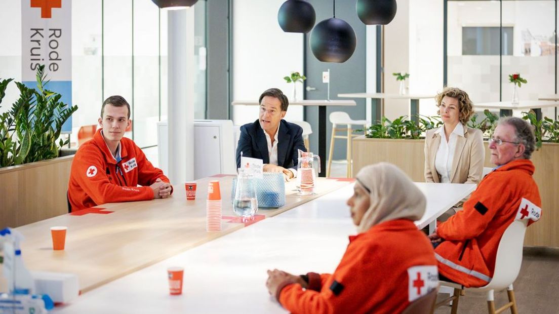 Medewerkers van het Rode Kruis praten met minister-president Mark Rutte.