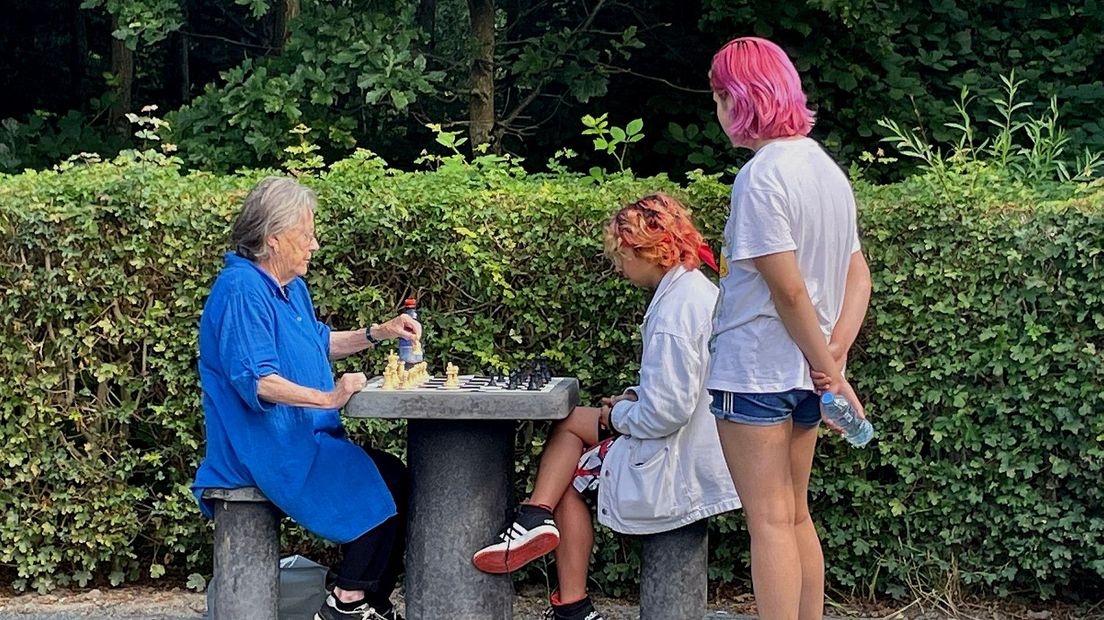 Een gepensioneerde schaakster en jonge tegenstander aan de schaaktafel in het Máximapark.