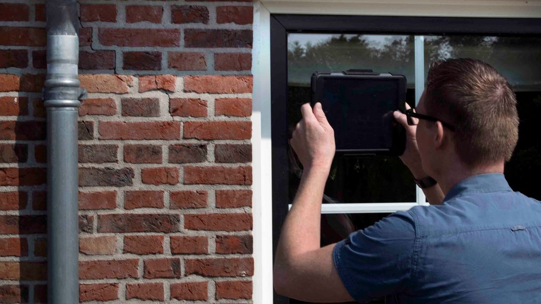Een man fotografeert een scheur in Bedum