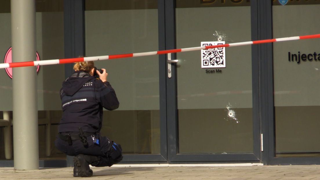 De forensische recherche fotografeert de voordeur waarop twee kogelgaten zichtbaar zijn.