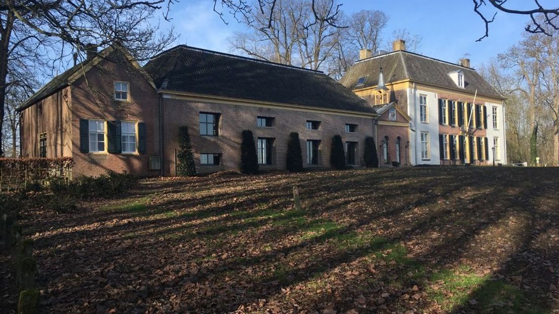 De middeleeuwse kasteelruïne ligt verscholen achter dit landhuis.