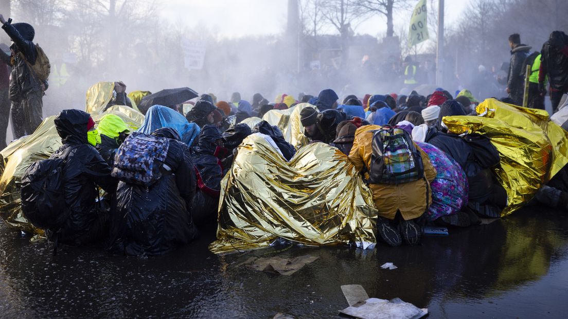 Actievoerders zitten natgespoten op het asfalt