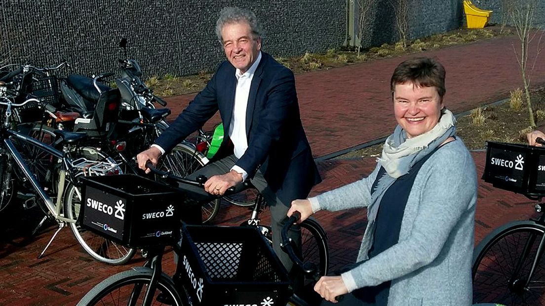 Wethouders Rost van Tonningen en Brommersma op een campusbike.